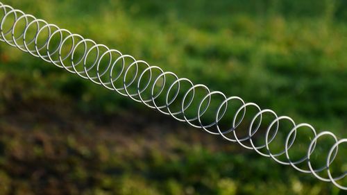 Close-up of spiral metal fence at cattle pasture