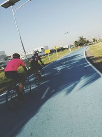 People riding bicycle on road against clear sky