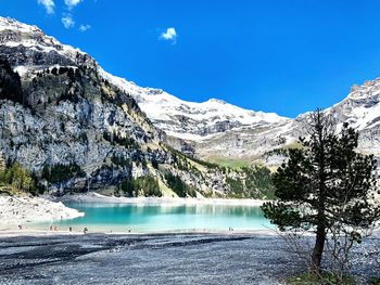 Scenic view of lake by snowcapped mountains against sky