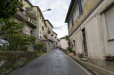 Empty road amidst buildings against sky