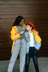 Portrait of smiling young woman standing against wall
