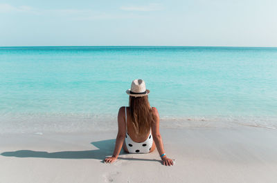 Rear view of woman wearing hat looking at sea against sky