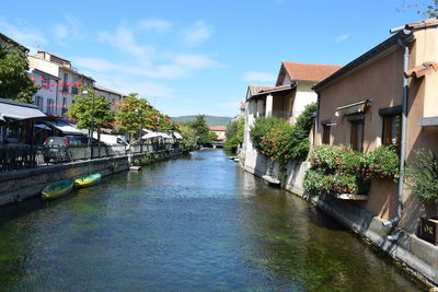 Canal amidst houses against sky in city