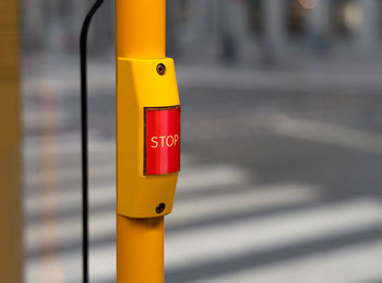 Close-up of yellow sign on pole in city