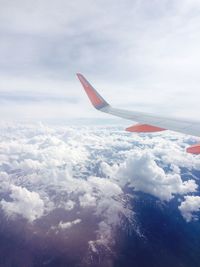 Aerial view of airplane wing over clouds