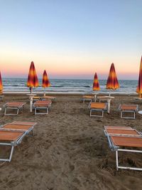 People at beach against clear sky during sunset