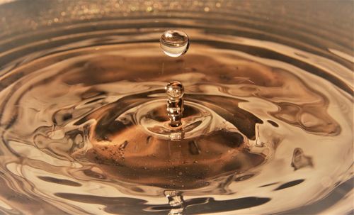 Golden water droplets splashing close up creating ripples