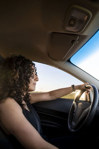 Young serious woman driving a car on the road.