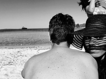 Portrait of woman sitting by man at beach