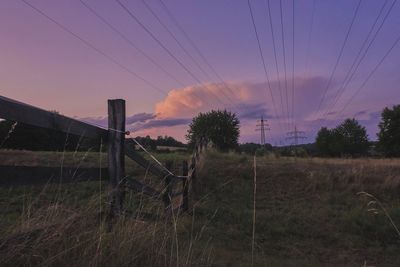 Electricity pylon on field against sky during sunset