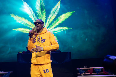 Young man holding yellow while standing against illuminated stage