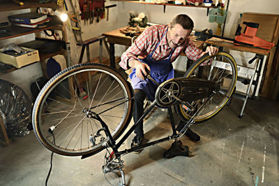 Senior man checking bicycle in his workshop