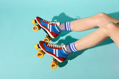 Low section of woman wearing skates over blue background