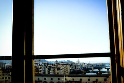 Buildings against clear sky seen through glass window