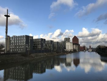 Buildings by river against sky in city