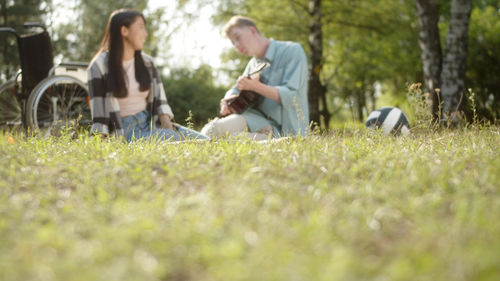 Side view of couple sitting on grassy field