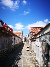 Alley amidst houses against sky