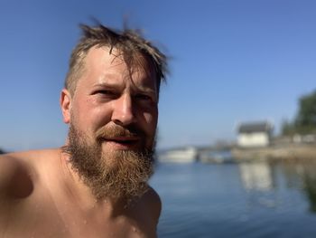 Portrait of shirtless bearded man standing at beach