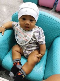 Portrait of baby boy sitting on blue sofa