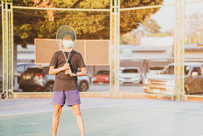 Boy holding tennis racket standing outdoors