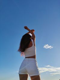 Rear view of woman standing against blue sky