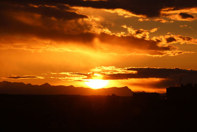 Silhouette landscape against dramatic sky during sunset