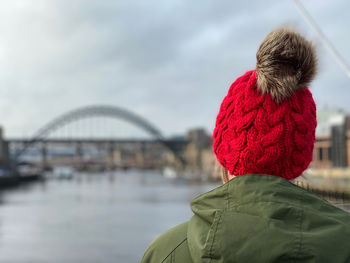 Rear view of woman standing on a bridge wearing a knit hat