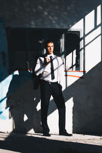 Portrait of young man standing against wall