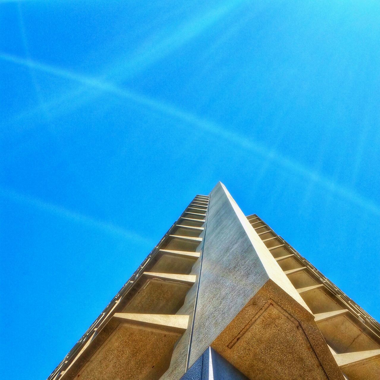 low angle view, architecture, blue, built structure, building exterior, clear sky, sky, sunlight, modern, day, outdoors, tall - high, high section, no people, building, tower, city, copy space, pattern, architectural feature