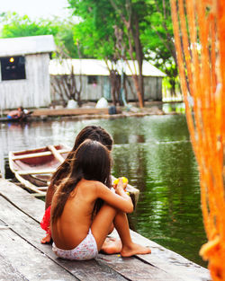 Rear view of woman sitting on wood