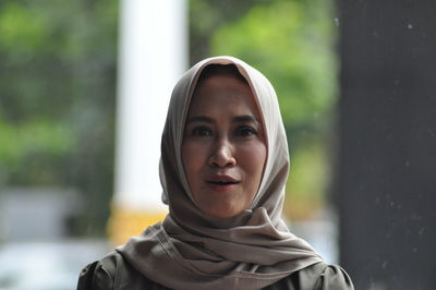 Portrait of young woman standing against blurred background