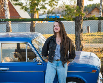Portrait of teenage girl standing by car