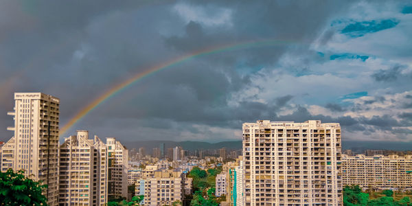 Rainbow over buildings in city against sky