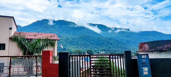 Built structure by building and mountains against sky