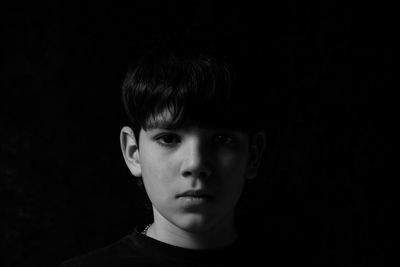 Portrait of young woman against black background