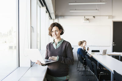 Portrait of professor using laptop in classroom