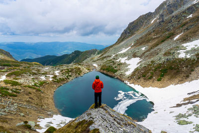 Rear view of man standing by mountain against sky