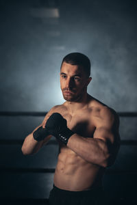 Portrait of young man exercising against black background