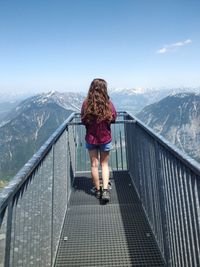 Rear view of woman standing by railing on observation point against sky