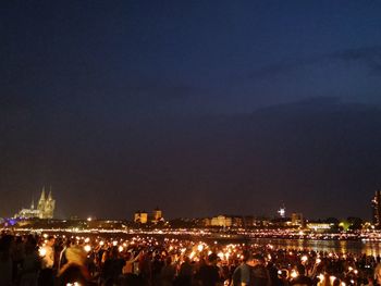 Crowd at illuminated city against sky at night