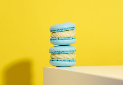 Baked blue round macarons on a yellow background, delicious dessert