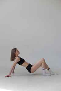 Woman sitting on wall against white background