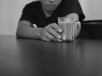 Midsection of man drinking coffee cup on table