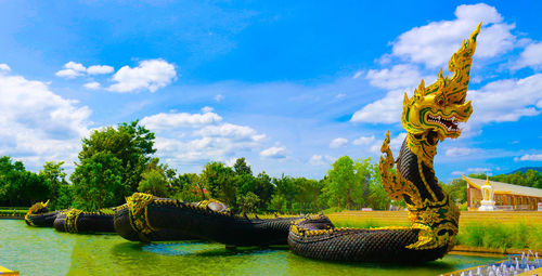 Snake sculpture on river against sky