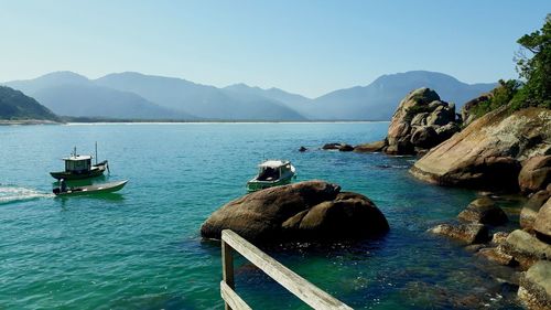 Scenic view of sea and mountains against clear sky