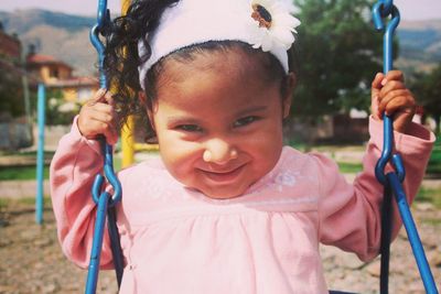 Portrait of smiling girl on swing at playground