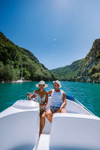 People on boat in sea against blue sky