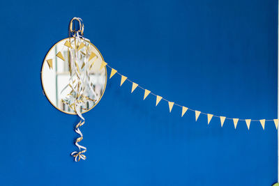 Low angle view of lighting equipment hanging against blue sky