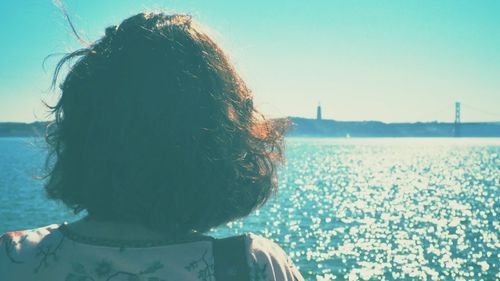 Rear view of woman on beach against clear sky