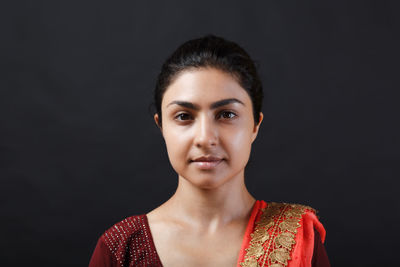 Portrait of young woman against black background